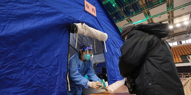 A medical worker hands fever medicine to a resident at a makeshift fever clinic set up inside a stadium, amid the coronavirus disease (COVID-19) outbreak in Beijing, China December 14, 2022. 