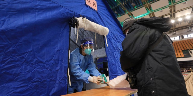 A medical worker hands fever medicine to a resident at a makeshift fever clinic set up inside a stadium, amid the coronavirus disease (COVID-19) outbreak in Beijing, China December 14, 2022. 