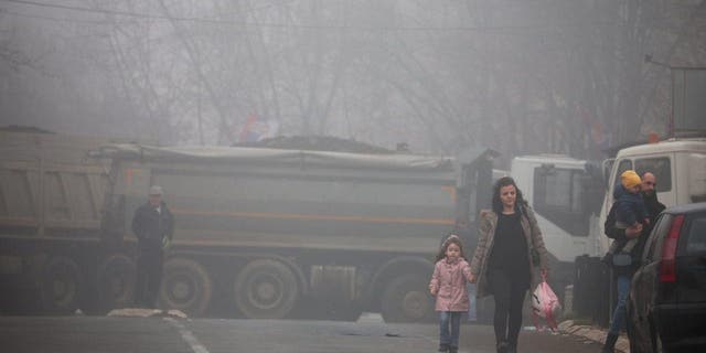 Local Serbs walk near a roadblock, near the northern part of the ethnically-divided town of Mitrovica, Kosovo, Dec. 27, 2022. 