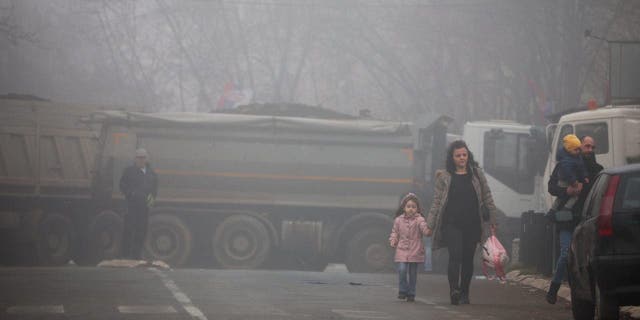 Local Serbs walk near a roadblock, near the northern part of the ethnically-divided town of Mitrovica, Kosovo, Dec. 27, 2022.