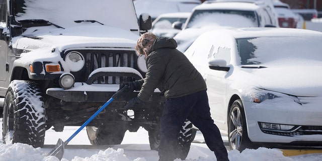 A man clears a path to vehicles parked in a lot Thursday, Dec. 22, 2022, in Denver. Temperatures plunged far and fast Thursday as a winter storm formed ahead of Christmas weekend, promising heavy snow, ice, flooding and powerful winds across a broad swath of the country and complicating holiday travel. (AP Photo/David Zalubowski)