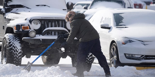 A man clears a path to vehicles parked in a lot Thursday, Dec. 22, 2022, in Denver. Temperatures plunged far and fast Thursday as a winter storm formed ahead of Christmas weekend, promising heavy snow, ice, flooding and powerful winds across a broad swath of the country and complicating holiday travel. (AP Photo/David Zalubowski)