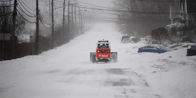 Bobcat makes its way to help dig out abandoned vehicles along the Lake Erie shoreline on December 24, 2022, in Hamburg, New York.