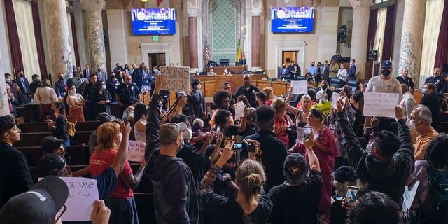 People hold signs before the cancelation of the Los Angeles City Council meeting on Oct. 12, 2022 in California.