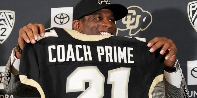 Deion Sanders sostiene una camiseta antes de hablar después de ser presentado como el nuevo entrenador en jefe de fútbol de la Universidad de Colorado durante una conferencia de prensa el domingo 4 de diciembre de 2022 en Boulder, Colorado.  Sanders dejó la Universidad Estatal de Jackson después de tres temporadas al frente del equipo de fútbol de la escuela.