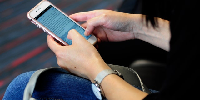 DALLAS, TEXAS - SEPTEMBER 21, 2017: A woman uses her smartphone while waiting to board her flight at Dallas/Fort Worth International Airport.