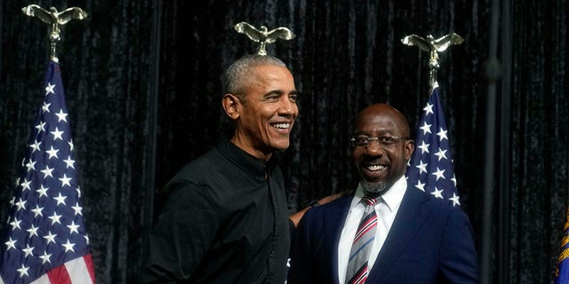 Former President Obama, left, greets Sen. Raphael Warnock, D-Ga., right, before Obama speaks during a rally on Dec. 1.