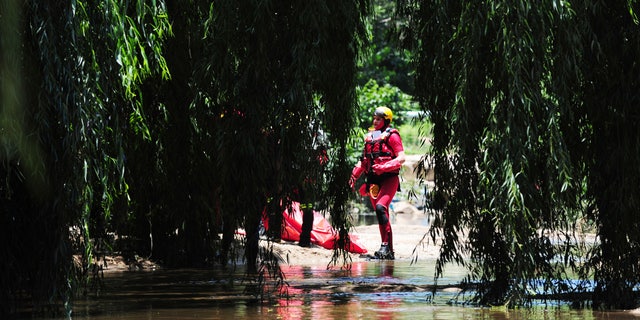 A rescue worker stands next to a body retrieved from the Jukskei river in Johannesburg, Sunday, Dec. 4, 2022. 