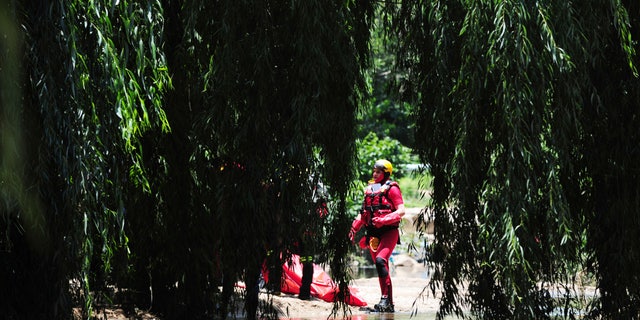 A rescue worker stands next to a body retrieved from the Jukskei river in Johannesburg, Sunday, Dec. 4, 2022.