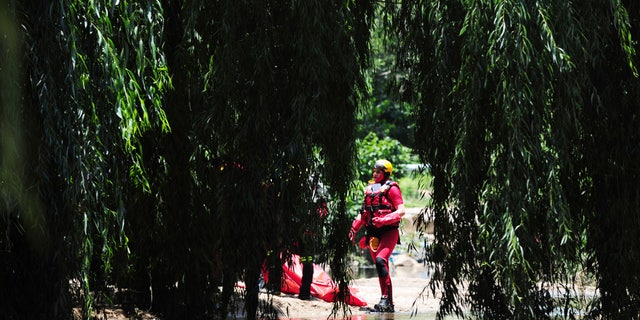 A rescue worker stands next to a body retrieved from the Jukskei river in Johannesburg, Sunday, Dec. 4, 2022. 