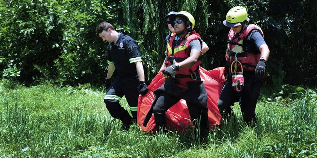 Rescuers carry the body of a flood victim that was retrieved from the Jukskei river in Johannesburg, Sunday, Dec. 4, 2022. 