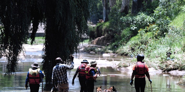 Rescue workers search the waters of the Jukskei river in Johannesburg, Sunday, Dec. 4, 2022. 