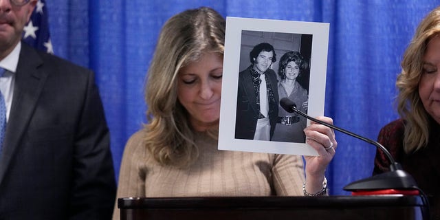 Randi Childs, daughter of Sheila Heiman, holds up a picture of her mother and father while speaking at a news conference after Richard Cottingham appeared remotely in a courtroom in Mineola, N.Y., Monday, Dec. 5, 2022. Cottingham, the serial murderer known as the "Torso Killer"admitted Monday to killing a 23-year-old woman outside a Long Island shopping mall in 1968 and four other women decades ago, including Sheila Heiman. 