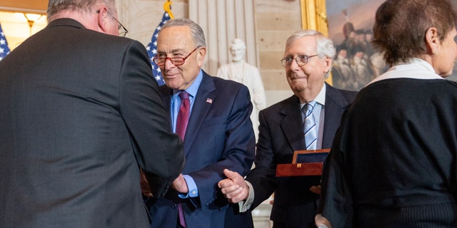 Craig Sicknick, left, brother of slain US Capitol Police Officer Brian Sicknick, is greeted by Senate Majority Leader Chuck Schumer of New York, with Senate Minority Leader Mitch McConnell of Kentucky and Gladys Sicknick, right, the mother of the Sicknicks.  The members of the Sicknick family declined to shake hands with McConnell and House Minority Leader Kevin McCarthy of Calif.