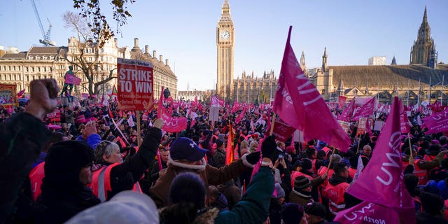 Royal Mail workers hold placards and banners as they gather in Parliament Square, to hold a protest over pay and jobs, in London, Friday, Dec. 9, 2022. The Communications Workers Union has planned six days of strike over pay. 