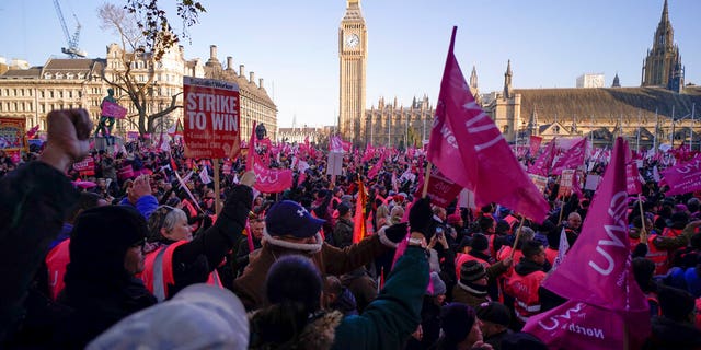 Royal Mail workers hold placards and banners as they gather in Parliament Square, to hold a protest over pay and jobs, in London, Friday, Dec. 9, 2022. The Communications Workers Union has planned six days of strike over pay. 