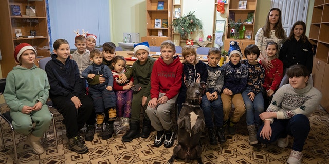 Children traumatized by the war pose for a photo with American Pit Bull Terrier "Bice" in the Center for Social and Psychological Rehabilitation in Boyarka near Kyiv, Ukraine, on Wednesday, Dec. 7, 2022.