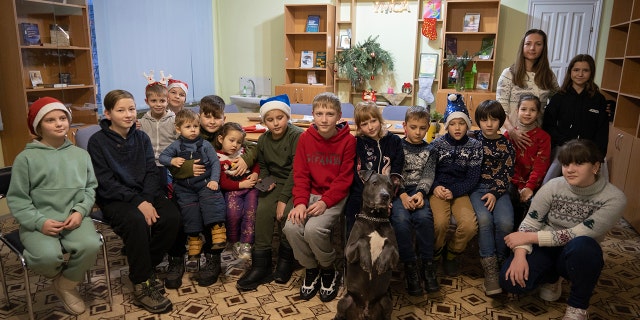 Children traumatized by the war pose for a photo with American Pit Bull Terrier "Bice" in the Center for Social and Psychological Rehabilitation in Boyarka near Kyiv, Ukraine, on Wednesday, Dec. 7, 2022.