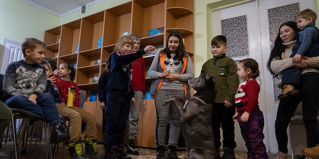 کودکان آسیب دیده از جنگ با پیت بول تریر آمریکایی بازی می کنند "Bice" در مرکز توانبخشی اجتماعی و رو، در بویارکا، نزدیک کیف، اوکراین، در روز چهارشنبه، 7 دسامبر 2022.