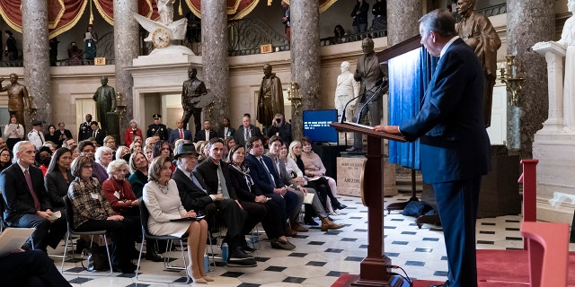 A presidente da Câmara, Nancy Pelosi, D, sentada à esquerda, é acompanhada por seu marido Paul Pelosi enquanto ouvem elogios do ex-presidente da Câmara John Boehner, à direita, durante a inauguração de seu retrato no Statuary Hall do Capitólio de Washington.  Quarta-feira, 14 de dezembro de 2022. 