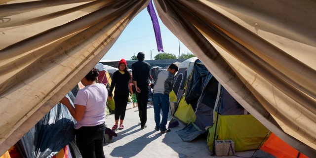 Migrants walk by their tents in the Senda de Vida 2 shelter in Reynosa, Mexico, Thursday, Dec. 15, 2022. 