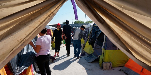 Migrants walk by their tents in the Senda de Vida 2 shelter in Reynosa, Mexico, Thursday, Dec. 15, 2022.