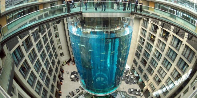 People gather on the top of the AquaDom aquarium at the Sea Life tourist attraction in Berlin, July 27, 2015. The aquarium burst on Friday, Dec. 16, 2022. 