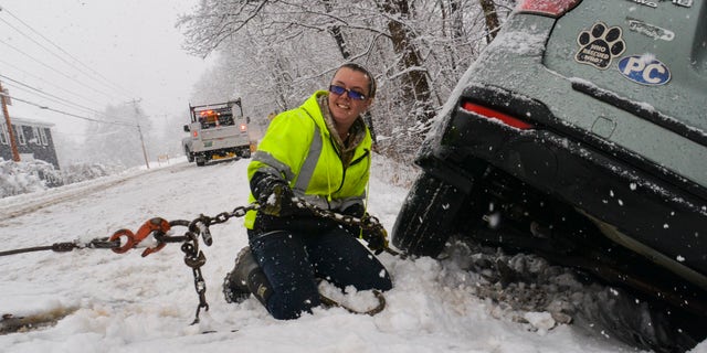 Brianna Brooks, proprietária da Scott Brooks Towing de Townshend, Vermont, trava um veículo em um caminhão-plataforma em um local de colisão de três veículos durante uma tempestade de neve na sexta-feira, 16 de dezembro de 2022. 