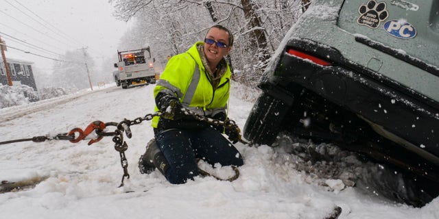 Brianna Brooks, owner of Scott Brooks Towing out of Townshend, Vermont, hooks up a vehicle to a flatbed truck at a three-vehicle crash site during a snowstorm on Friday, Dec. 16, 2022.