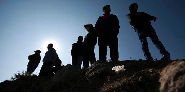 Migrants stand near the US-Mexico border in Ciudad Juarez, Mexico, Monday, Dec. 19, 2022. 