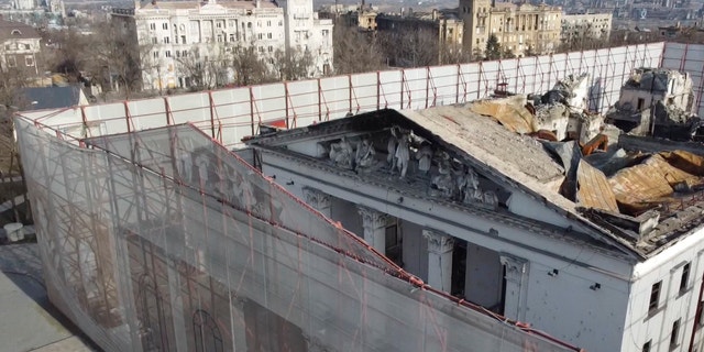 This December 2, 2022 video photo shows a fence surrounding the Drama Theater in Mariupol, Ukraine.  Months after hundreds were killed in Russian airstrikes on the theatre, the fence is etched with Russian and Ukrainian literary figures as well as outlines of the theatre's former lives, before the Russian occupation. 