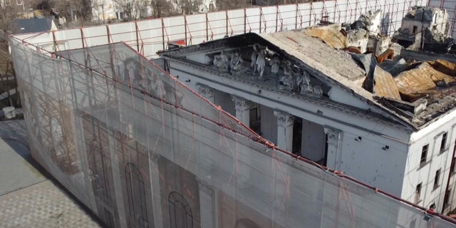 This December 2, 2022 video photo shows a fence surrounding the Drama Theater in Mariupol, Ukraine.  Months after hundreds were killed in Russian airstrikes on the theatre, the fence is etched with Russian and Ukrainian literary figures as well as outlines of the theatre's former lives, before the Russian occupation. 