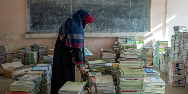 Amanah Nashenas, 45-year-old an Afghan teacher, collects books in a school in Kabul, Afghanistan, Thursday, Dec. 22, 2022. 