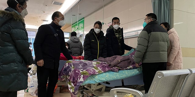 波州市にある第 4 朗房人民病院の救急部門で彼女の体が運ばれる前に、感情的な親類が静かに彼女の周りに集まり、最後の別れを告げる中、バイタリティの低い年配の女性の顔を覆うために男性が布を引っ張ります。 2022 年 12 月 22 日木曜日、中国北部の河北省で。 