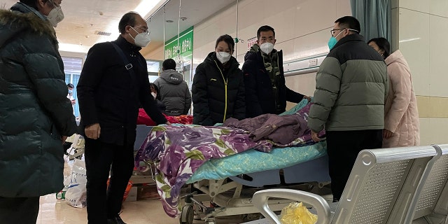 A man pulls a cloth to cover up the face of an elderly woman whose vitals flatlined as emotional relatives gather silently around her for a final farewell before her body is taken away at the emergency department of the Langfang No. 4 People's Hospital in Bazhou city in northern China's Hebei province on Thursday, Dec. 22, 2022. 