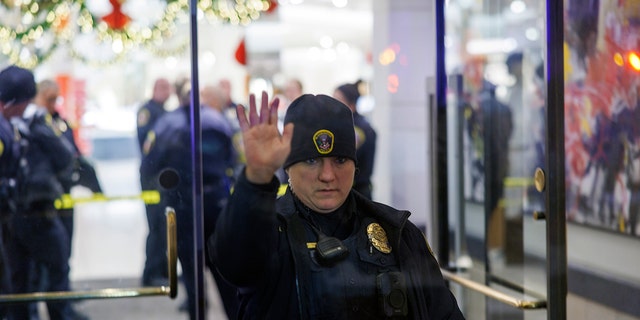 A Bloomington Police officer holds up a hand at the entrance to the Mall of America in Bloomington, Minn., after reports of shots fired on Friday, Dec. 23, 2022. 