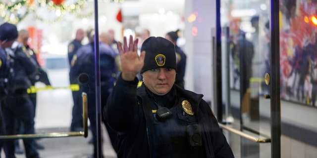 A Bloomington Police officer holds up a hand at the entrance to the Mall of America in Bloomington, Minn., after reports of shots fired on Friday, Dec. 23, 2022. 