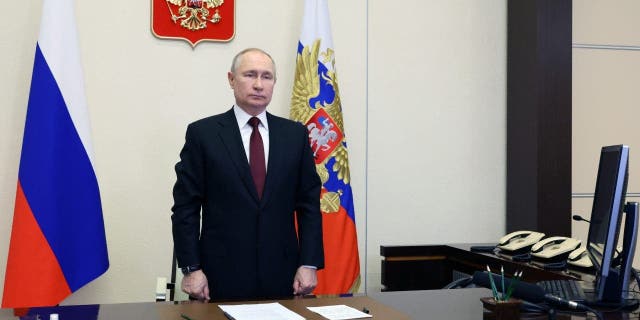 Russian President Vladimir Putin listens to the national anthem as he oversees the commissioning of new ships for the Russian navy via video conference at the Novo-Ogaryovo residence outside Moscow, Russia, Thursday, Dec. 29, 2022.