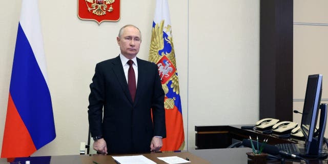 Russian President Vladimir Putin listens to the national anthem as he oversees the commissioning of new ships for the Russian navy via video conference at the Novo-Ogaryovo residence outside Moscow, Russia, Thursday, Dec. 29, 2022. 