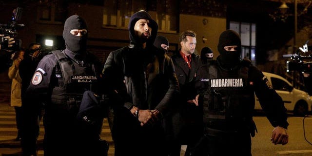 Andrew Tate et Tristan Tate sont escortés par des policiers devant le siège de la Direction des enquêtes sur le crime organisé et le terrorisme à Bucarest (DIICOT) après avoir été détenus pendant 24 heures, à Bucarest, Roumanie, le 29 décembre 2022. 