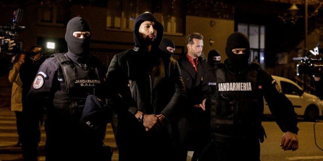 Andrew Tate and Tristan Tate are escorted by police officers outside the headquarters of the Directorate for Investigating Organized Crime and Terrorism in Bucharest (DIICOT) after being detained for 24 hours, in Bucharest, Romania, December 29, 2022.