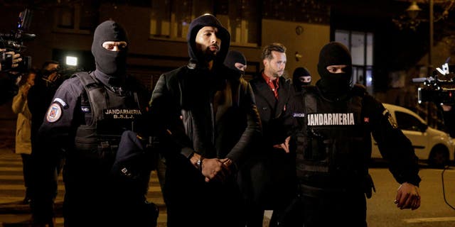 Andrew Tate and Tristan Tate are escorted by police officers outside the headquarters of the Directorate for Investigating Organized Crime and Terrorism in Bucharest (DIICOT) after being detained for 24 hours, in Bucharest, Romania, December 29, 2022. Inquam Photos/Octav Ganea via REUTERS