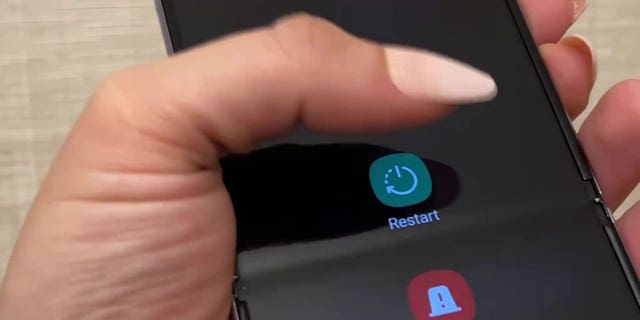 一位女士正在重启她的 Android 智能手机的照片。