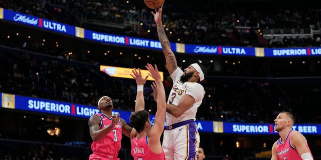 Los Angeles Lakers forward Anthony Davis, center, scores as Washington Wizards guard Bradley Beal, left, and forward Deni Avdija (9) defend during the first half of an NBA basketball game, Sunday, Dec. 4, 2022, in Washington.