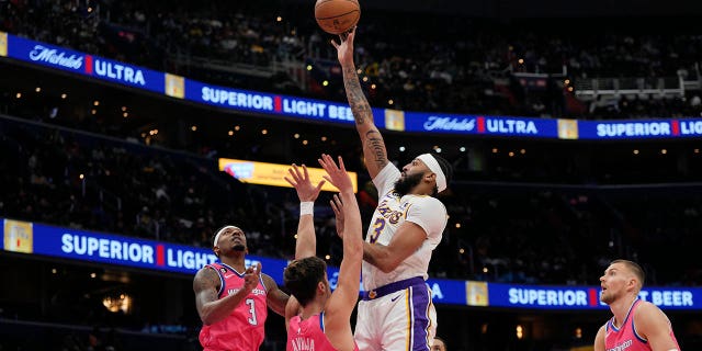 Los Angeles Lakers forward Anthony Davis, center, scores as Washington Wizards guard Bradley Beal, left, and forward Deni Avdija (9) defend during the first half of an NBA basketball game, Sunday, Dec. 4, 2022, in Washington.