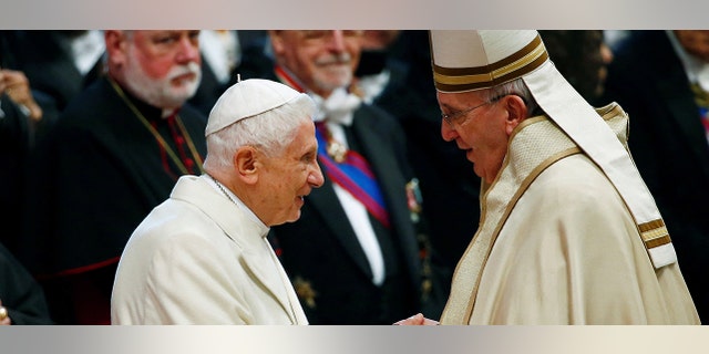 FILE PHOTO: Pope Francis greets Pope Emeritus Benedict XVI during a mass to create 20 new cardinals during a ceremony in St. Peter's Basilica at the Vatican Feb. 14, 2015.