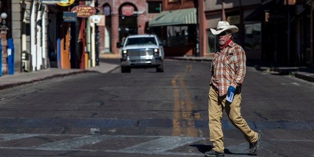 A man in a hat walks across Main Street Tuesday, May 26, 2020, in Bisbee, AZ. Bisbee is located in Cochise County.