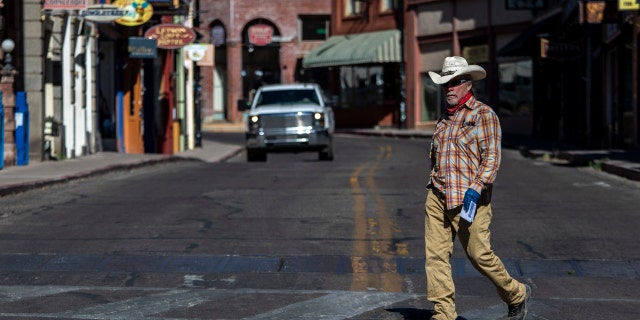 A man in a hat walks across Main Street Tuesday, May 26, 2020, in Bisbee, AZ.  Bisbee is located in Cochise County.