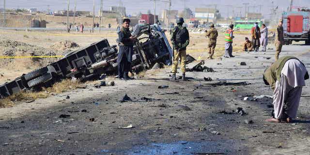 Investigators gather evidence at the site of a suicide bombing on the outskirts of Quetta, Pakistan.  On September 30, 2022, a suicide bomber blew himself up near a truckload of police officers on their way to protect polio workers outside of Quetta.