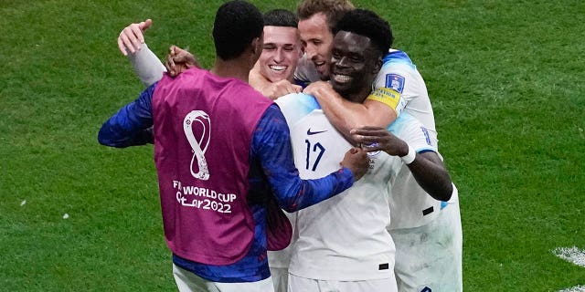 England's Bukayo Saka, right, celebrates with teammates after scoring during the World Cup match against Senegal at Al Bayt Stadium in Al Khor, Qatar, Dec. 4, 2022.